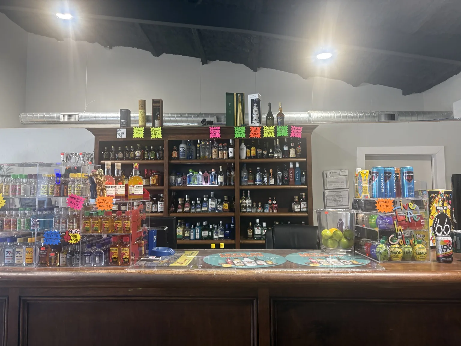 A wide view of One Stop Liquor’s wooden checkout counter with miniature bottles, spirits, canned cocktails and mixers