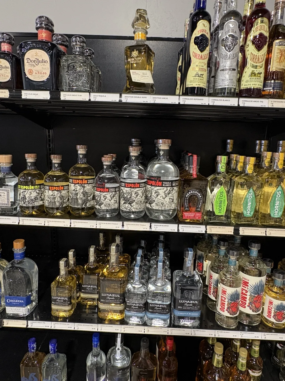 Don Julio, Espolòn and Hornitos tequila alongside other tequila bottles on black shelves at One Stop Liquor in Bethany, Oklahoma