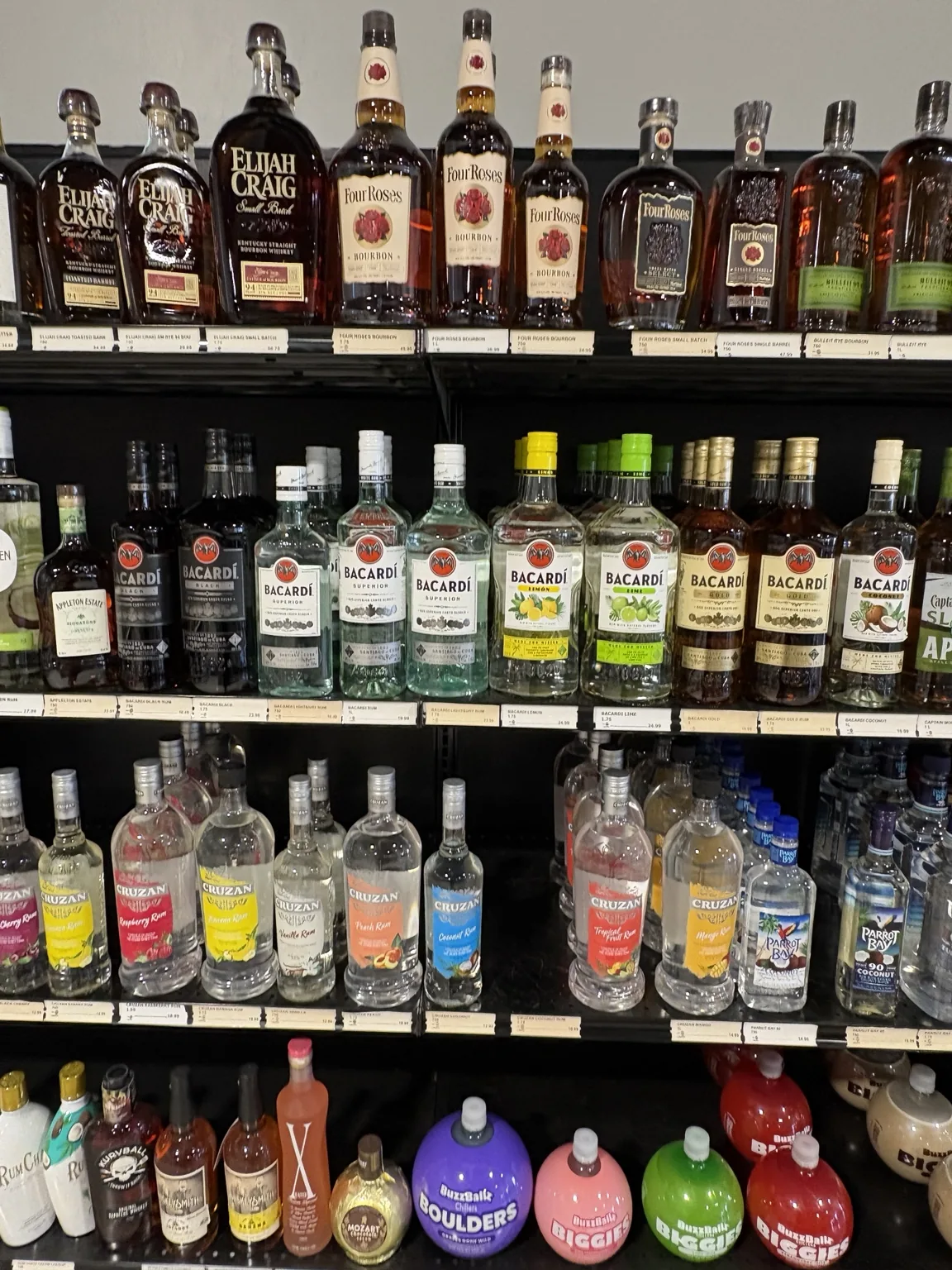 Elijah Craig and Evan Williams bourbon above Bacardí rum and other spirits at One Stop Liquor in Bethany, Oklahoma