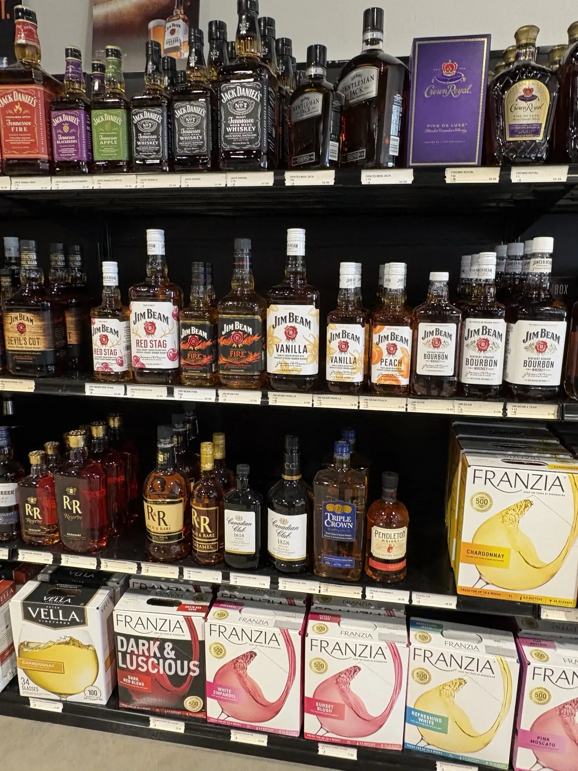 Jack Daniel’s and Crown Royal bottles above Jim Beam whiskeys and Franzia boxed wine at One Stop Liquor in Bethany, Oklahoma