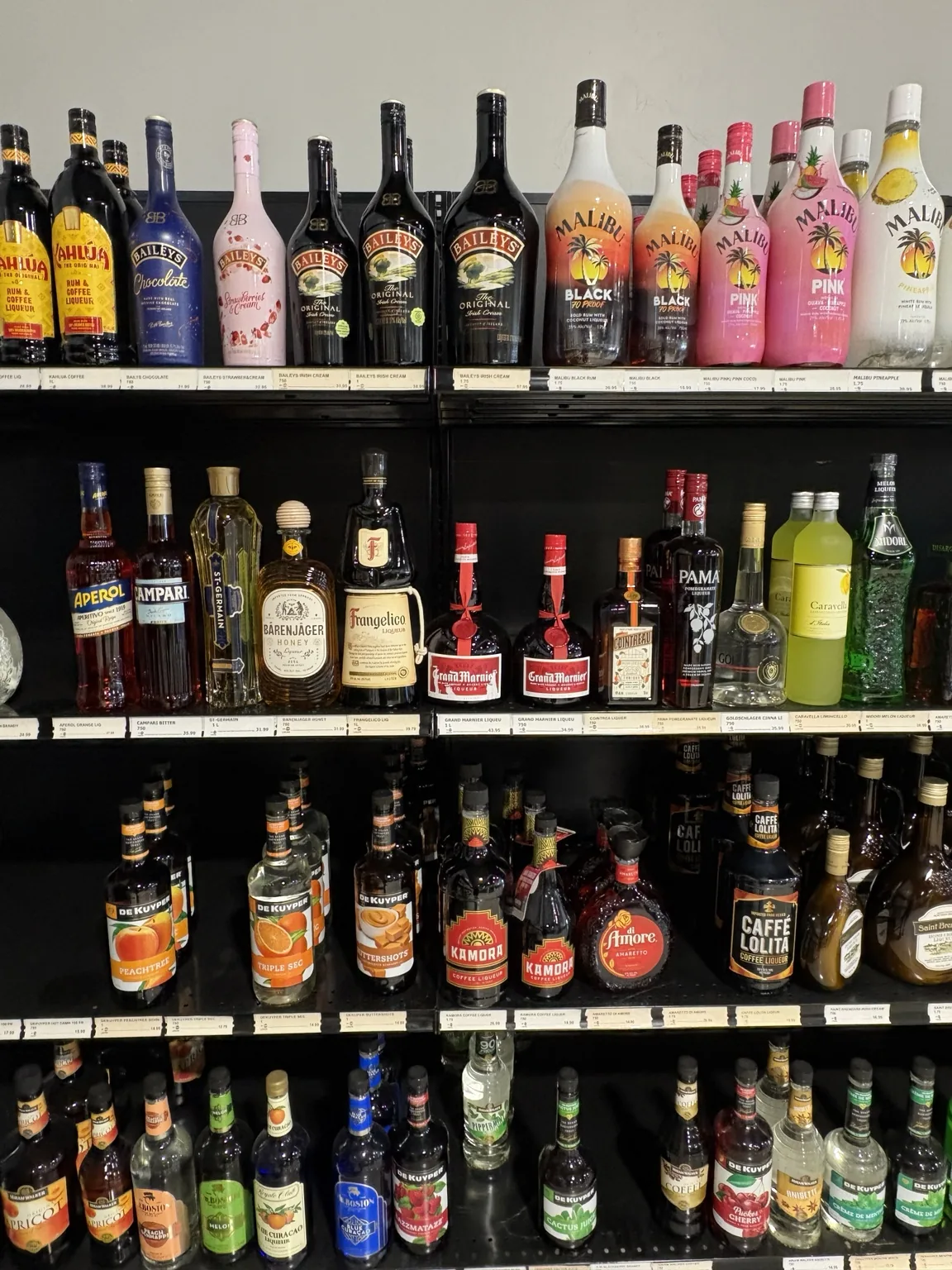 Malibu rum and Baileys bottles above liqueurs and cocktail ingredients at One Stop Liquor in Bethany, Oklahoma