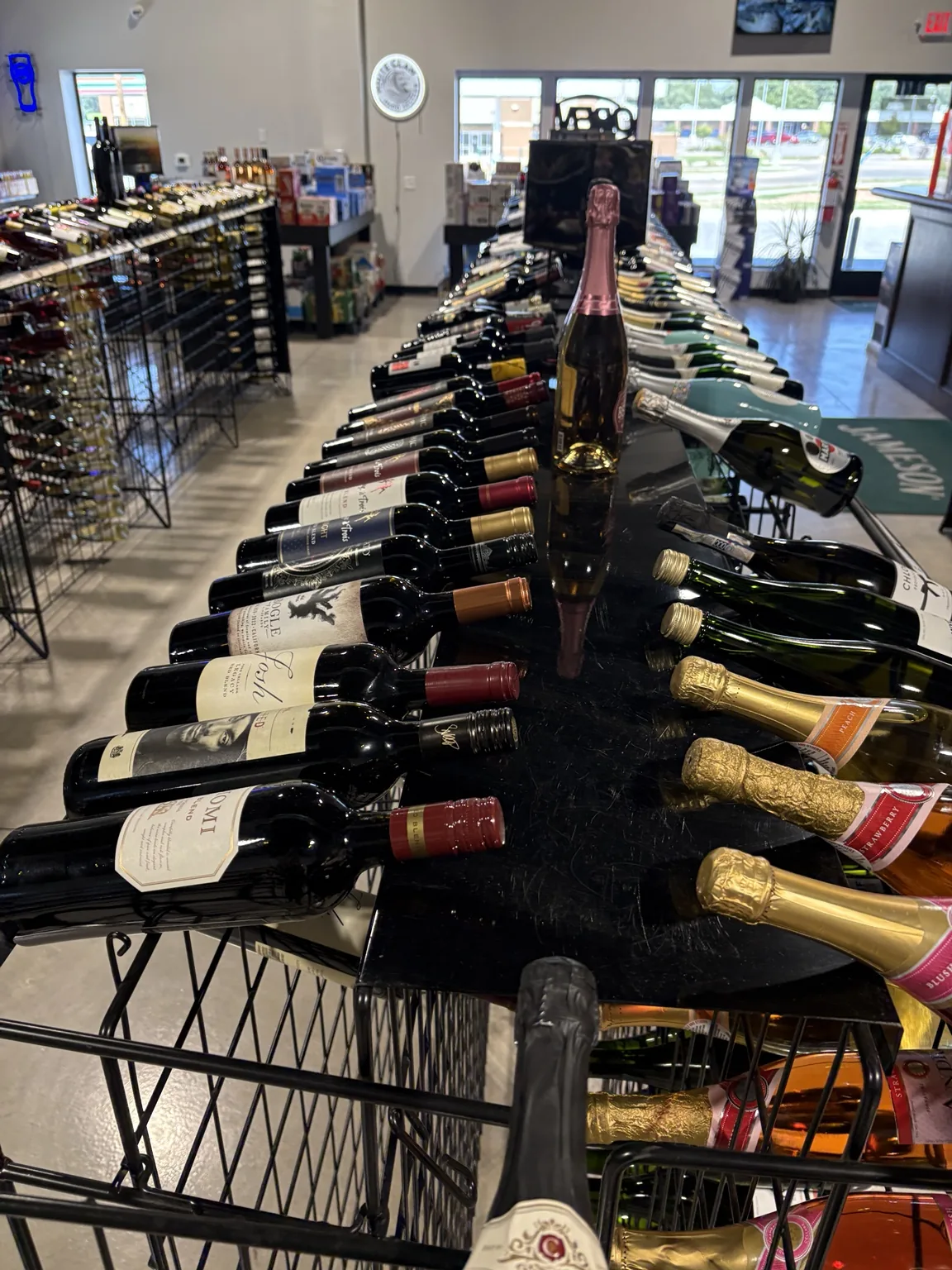 Red and sparkling wine bottles arranged in a wire rack near the store entrance at One Stop Liquor in Bethany, Oklahoma