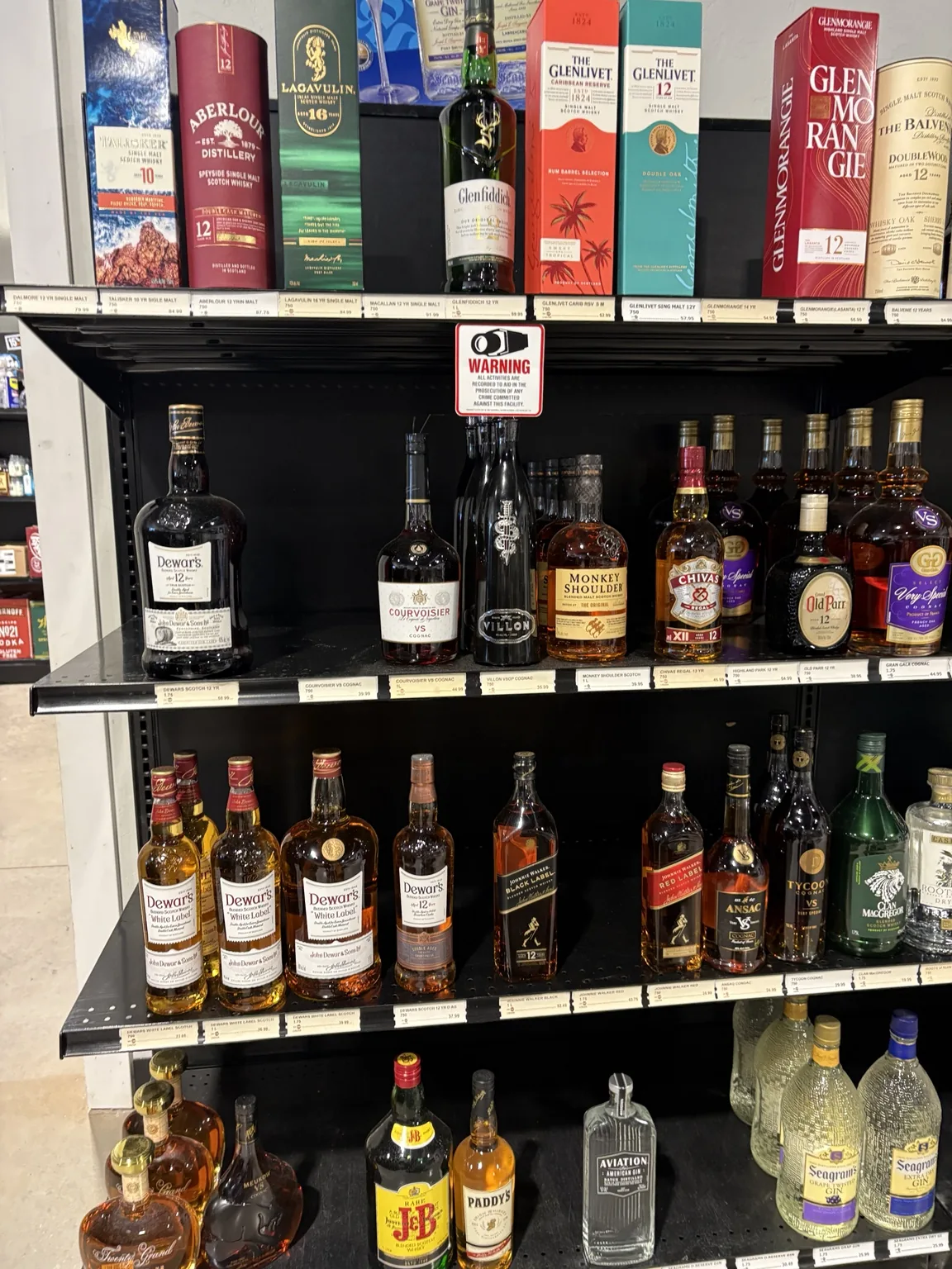 Talisker, Aberlour, Lagavulin and Glenlivet boxes above Dewar’s, Monkey Shoulder and cognac bottles at One Stop Liquor in Bethany, Oklahoma