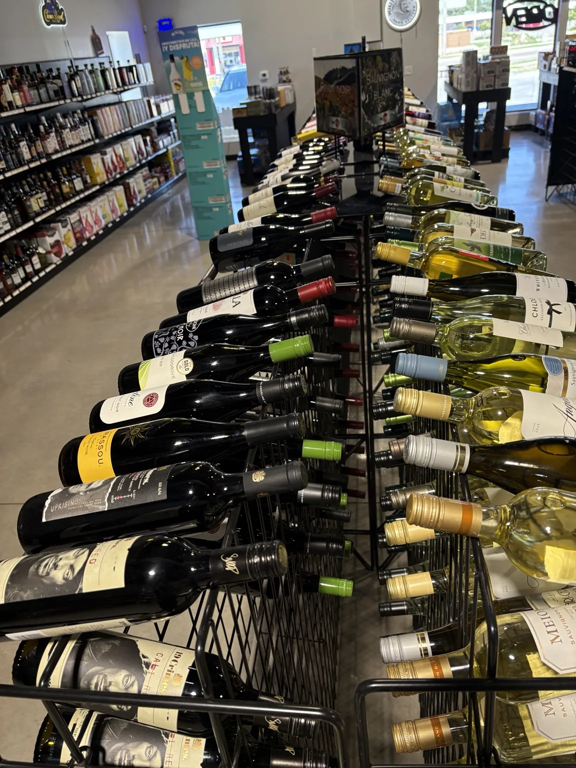 White and red wine bottles in wire racks beside the wine aisle at One Stop Liquor in Bethany, Oklahoma